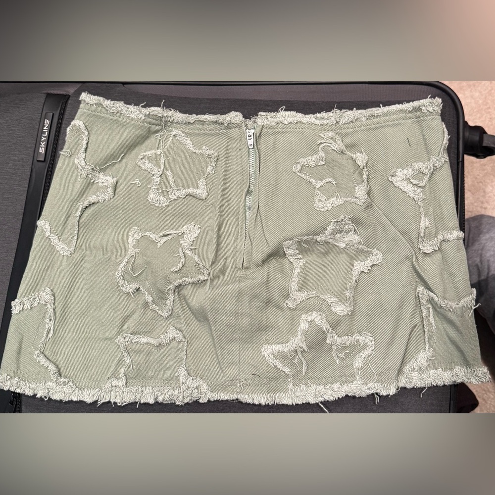 Olive green denim mini skirt with frayed star-shaped cutouts and a back zipper